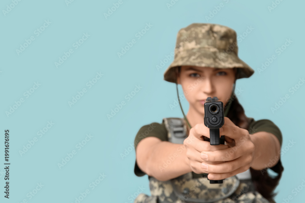 Fototapeta premium Confident young female soldier with handgun on blue background, closeup
