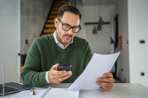 Man multitasking working from home using phone and documents