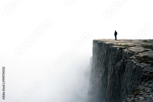 A man stands on the edge of a high cliff in a thick fog. Space for text.