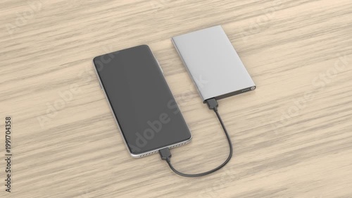 Smartphone charging with a power bank on a wooden desk