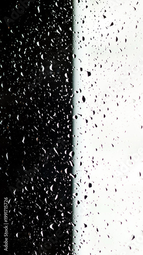 Minimalist texture of water drops on a glass surface. Rain on a clear window split into black and white sections creating a strong visual contrast