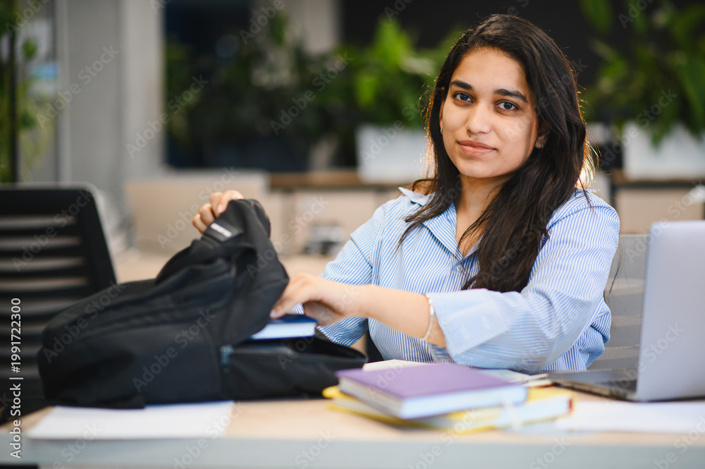 Obraz premium Indian female student taking books from backpack