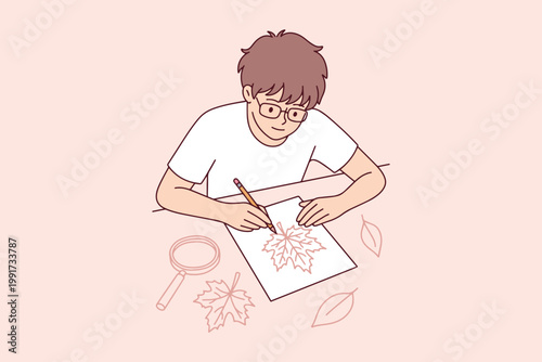 Schoolboy studying nature and drawing fallen leaves. Kid using magnifying glass to see details of autumn foliage. Back to school and art education.