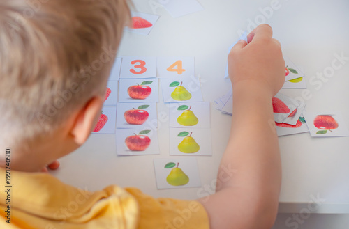  Little boy learning to count with fruit flashcards and numbers