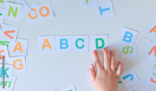 Close up of a toddler learning the alphabet and basic literacy. A child's hand arranges 