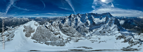 Aerial view of snow-capped peaks rise majestically against a brilliant blue sky streaked with wispy clouds, Garmisch-Patenkirchen, Bavaria, Germany.