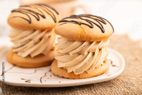 Caramel Cream Cakes on white wooden, linen textile, cup of coffee, side view, close up, selective focus