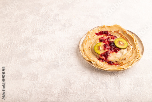 Stack of Plain Fried pancakes with jam and kiwi on gray concrete. side view, copy space