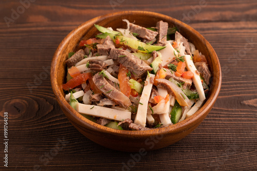Meat salad with beef and vegetables on brown wooden, top view, close up