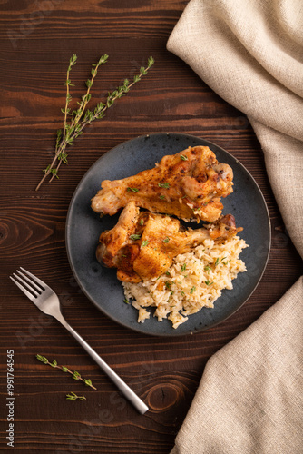 Fried Turkey Wing with spices and thyme on plate on brown wooden, top view, close up