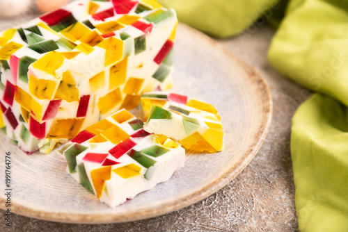 Colored Fruit and milk jelly on brown concrete, side view, close up, selective focus