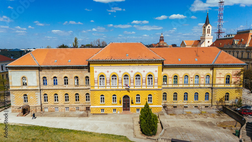 Aerial view of the bright yellow facade of a building, contrasting against the terracotta roof and blue sky, Zrenjanin, Vojvodina, Serbia.