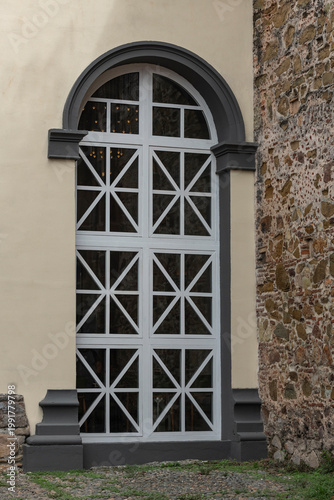 Historic building window with decorative grilles contrasting against a beige stucco facade and a natural stone wall, highlighting the architectural heritage of Casco viejo, Panama city - stock photo