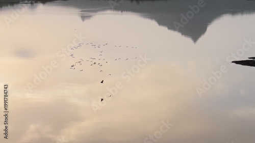 Moving drone shot of Sunset over a lake with dramatic clouds and Mountains in the background shot during monsoon. 4K60fps