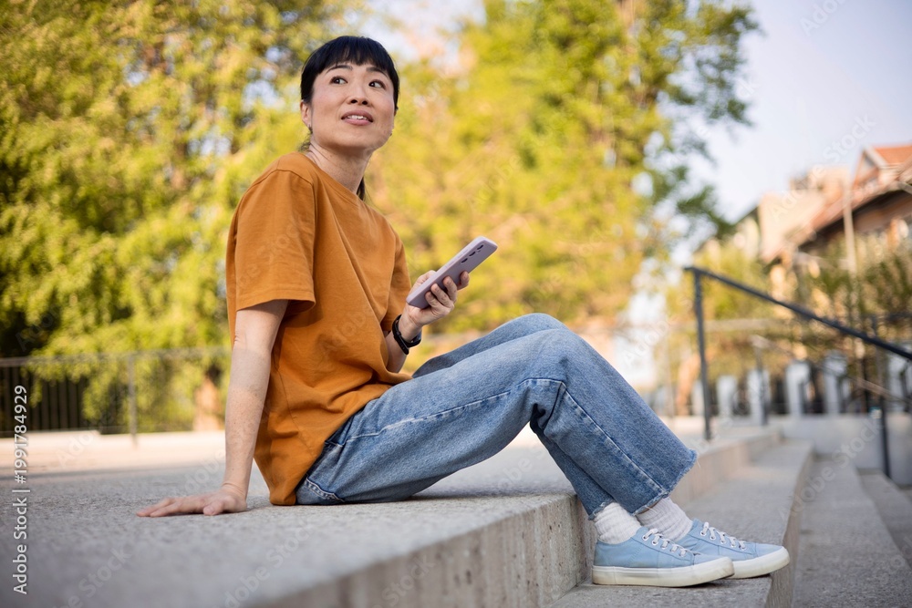 Obraz premium Female using smartphone while sitting in park
