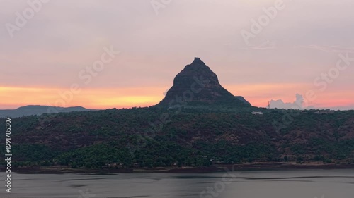 Moving drone shot of Sunset over a lake with dramatic clouds and Mountains in the background shot during monsoon. 4K60fps