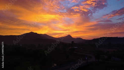 Drone shot of a sunset over a mountain during golden hour with extreme orange colours 4K30