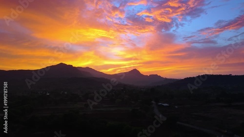 Drone shot of a sunset over a mountain during golden hour with extreme orange colours 4K30