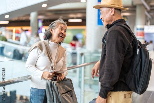 Senior asian traveler couple smiling at airport with suitcases show excitement before travel, retirement lifestyle, planning international journey, travel insurance for elderly, tour and global trip