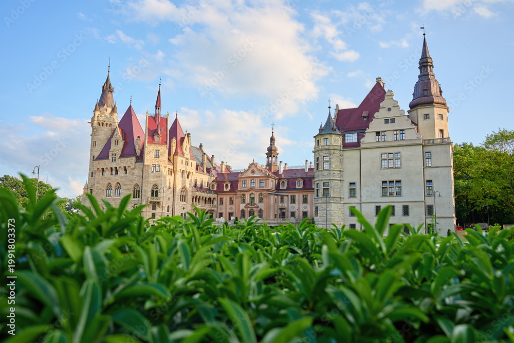 Fototapeta premium Historic Moszna Castle with towers and ornate facade above green hedge in Moszna, Poland. Concept of architecture, cultural heritage and travel destination.