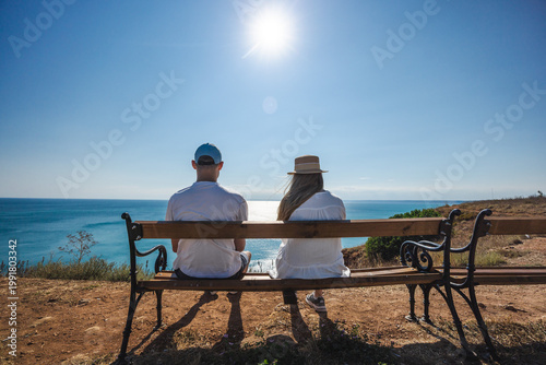 Photos Couple sitting on bench overlooking Black Sea coast under bright summer sun in B
