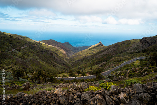 Scenic empty road surrounded by tropical vegetation, palm trees and mountains. Ideal for travel, road trip, freedom and adventure concepts.