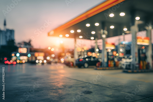 Blurred view of a gas station at dusk with cars and lights.