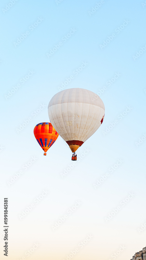 Obraz premium Hot air balloons rise into the clear sky over the countryside at dawn near a small town