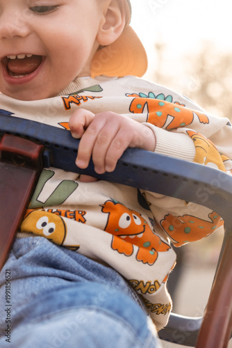 Smiling child on swing with fox-patterned sweater Close up