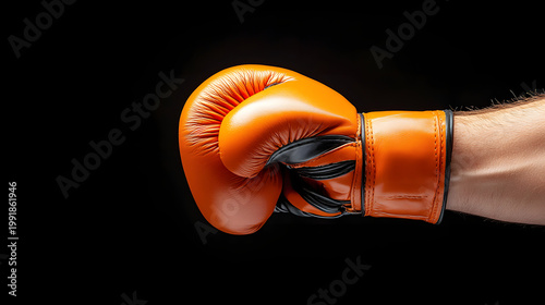 Boxing glove orange fist punch hand combat sport close up black background Orange boxing glove clenched fist close up black background, combat sport strength training concept with dramatic