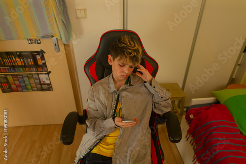 Teenager posing during study break on chair checking smartphone, distracted glance between notes and messages bedroom study nook with desk items, soft curtain light and casual clothes