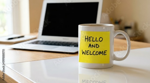 A coffee mug displays a welcome message next to an open laptop on a desk