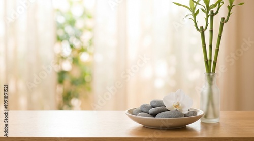 A serene still life of a bowl with stones and a flower on a wooden table next to a vase with branches in a bright room.
