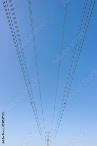 A large amount of high-tension electrical wires in a geometric position against the blue sky