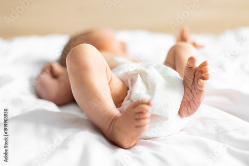 Fotografía Close-up of a Caucasian newborn baby's tiny feet and legs, wearing a diaper and