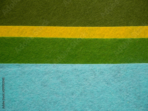 Photography Close-up flat lay of colorful felt fabric sheets arranged in bold color blocks — light cream beige, dark olive green, bright yellow, grass green, and turquoise sky blue