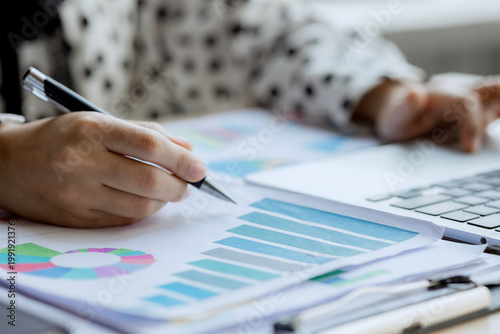 Smiling businesswoman working on laptop in café, enjoying hot drink, analyzing charts, planning projects, and staying connected in a modern professional lifestyle.
