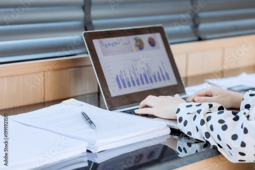 Smiling businesswoman working on laptop in café, enjoying hot drink, analyzing charts, planning projects, and staying connected in a modern professional lifestyle.

