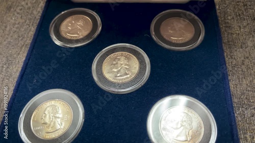 Close up video showing a complete 1999 United States quarter dollar coin set arranged inside a blue presentation box with protective capsules.