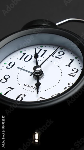 Old fashioned alarm clock with bells on black background. Vintage clock time flowing timelapse. Time concept. Vertical video. Table clock show running time. Close-up in 4K, UHD