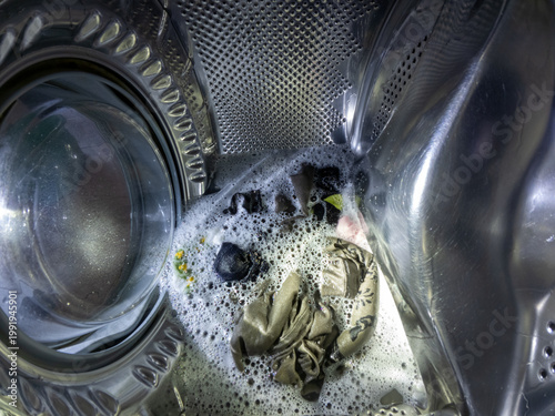 Washing Machine Interior with Wet Laundry and White Soap Foam