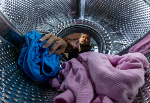 Man Loading Colorful Clothes into Washing Machine Drum, Inside View