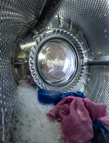 Inside View of Washing Machine Drum with Wet Laundry and Soap Suds