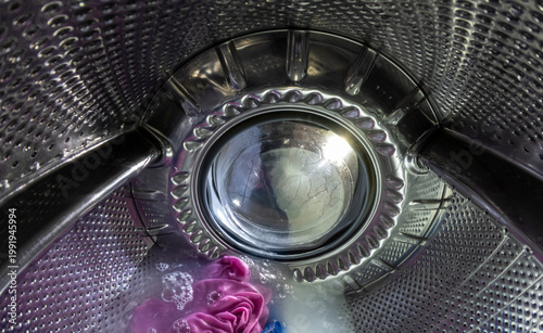 Inside View of Washing Machine Drum with Wet Laundry and Soap Suds