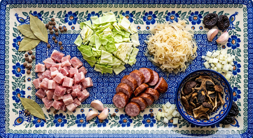 Hyper-realistic top view of Bigos stew ingredients on Polish blue pottery