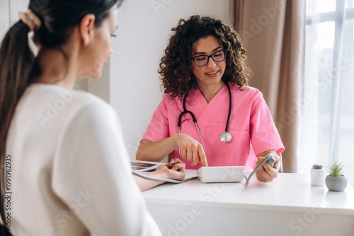 Bild auf Leinwand Female healthcare professional in pink scrubs discusses treatment options with p