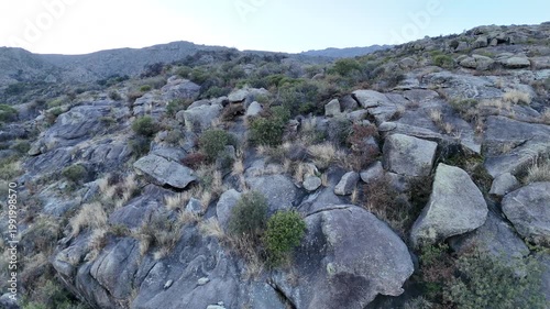 Trail runner training on a rocky mountain path in an arid landscape.