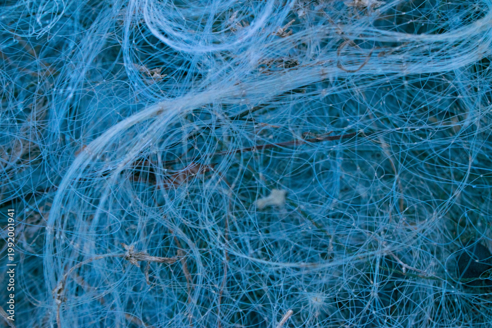 Obraz premium Close-up of tangled blue fishing net background. Abstract mesh texture of nylon threads.
