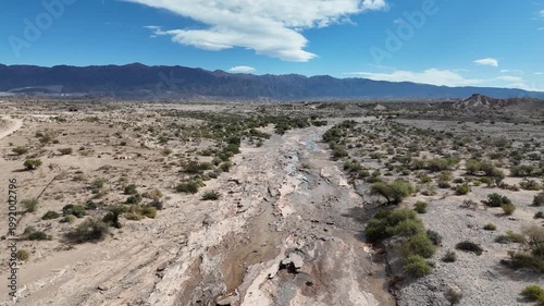Dry riverbed with mineral formations and cracked mud in arid landscape under blue sky