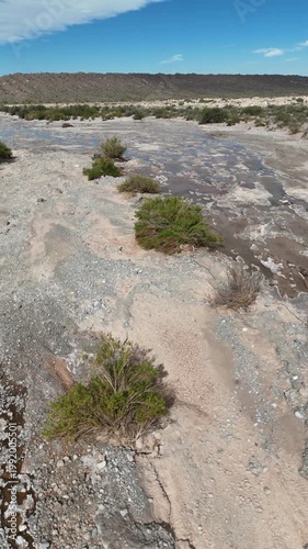 Dry riverbed with mineral formations and cracked mud in arid landscape under blue sky